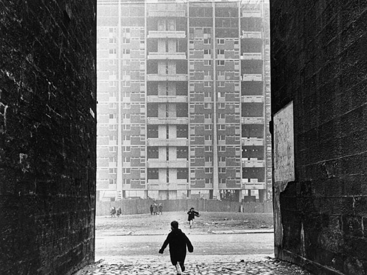 A child snapped mid-run down an alleyway in the Gorbals - a crane can be seen constructing a high-rise block of flats in the background.