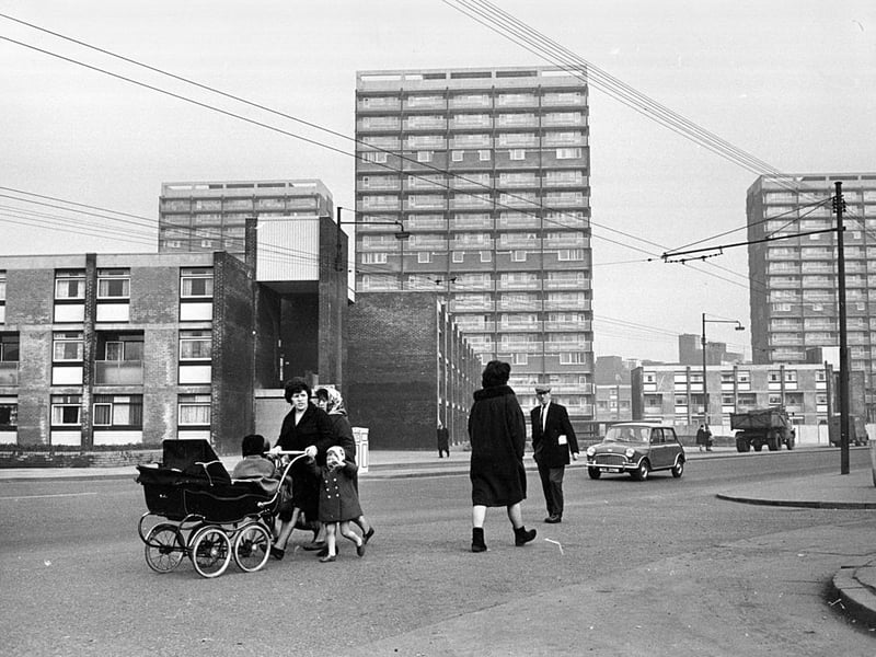 A child helps their mum push a pram through the freshly refurbished Gorbals.