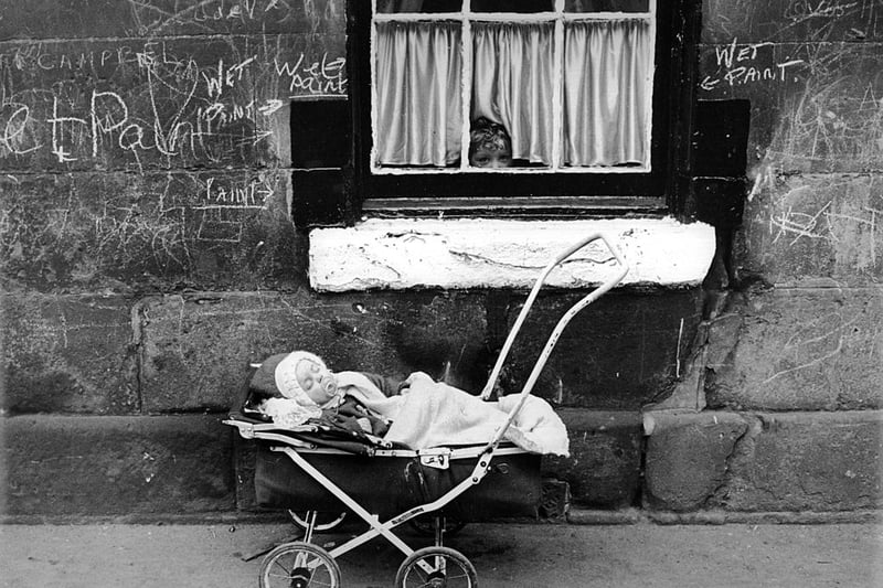 A child looks at a baby in a pram from the window of a tenement block in the Gorbals area of Glasgow - the building has long since been demolished.