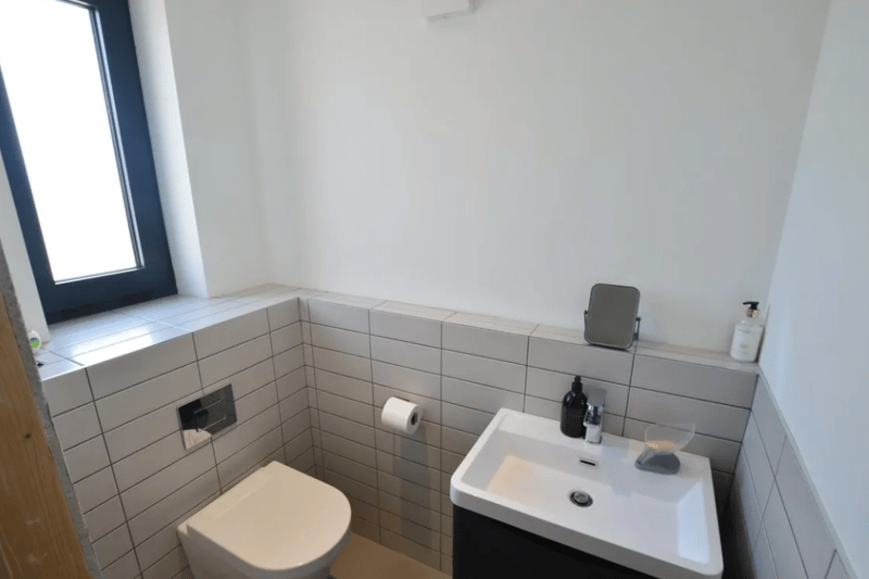A toilet and sink with very modern tiling seen here