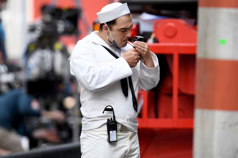 A sailor extra sparks a cigarette in between takes (Photo by Jeff J Mitchell/Getty Images)