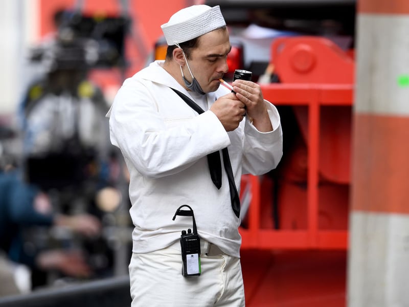 A sailor extra sparks a cigarette in between takes (Photo by Jeff J Mitchell/Getty Images)