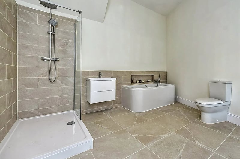 Bathroom - Bespoke wooden windows, part-tiled walls, tiled flooring, panelled bath with shower over.