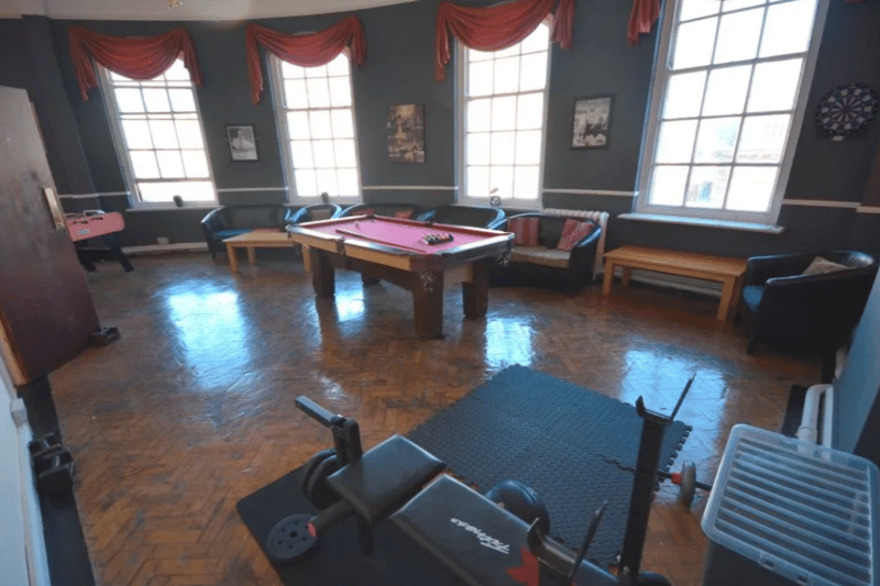 A multi use room with a pool table, gym equipment and more