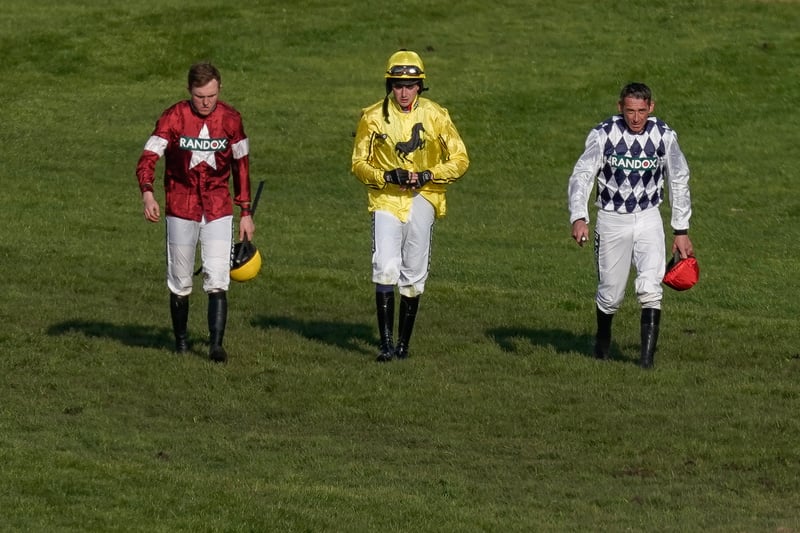 Jockeys return after being unseated or falling from their mounts during The Randox Grand National Handicap Chase 