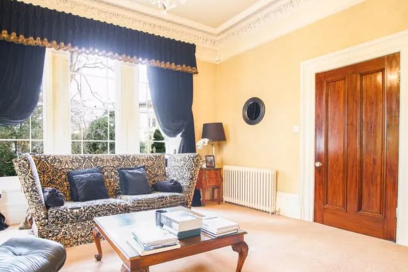 The property has three large reception rooms, including this living room with huge windows and high ceilings. 