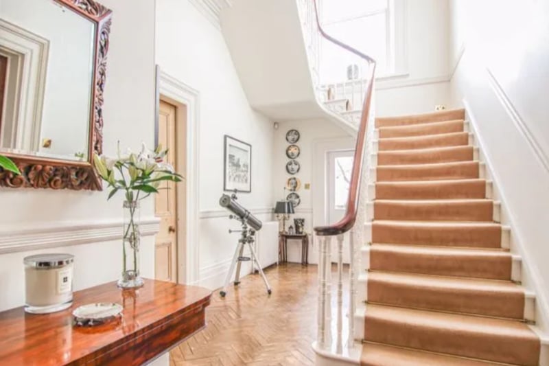 Upon entering, you are greeted with a stunning staircase and hallway with parquet flooring.
