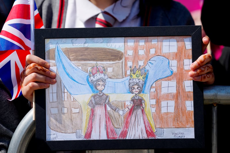 Children show drawings as they wait for the arrival of King Charles III and Camilla, the Queen Consort to visit Liverpool Central Library.