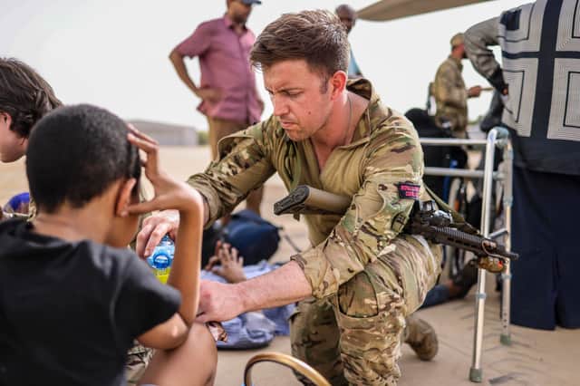 A Royal Marine looks after an evacuee whilst waiting at Wadi Saeedna airport in Sudan for an aircraft bound for Cyprus (Photo: Ministry of Defence/PA)