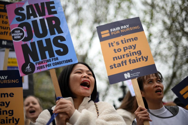 Healthcare workers hold placards as cross Westminster Bridge. (Photo by Daniel LEAL / AFP via Getty Images)