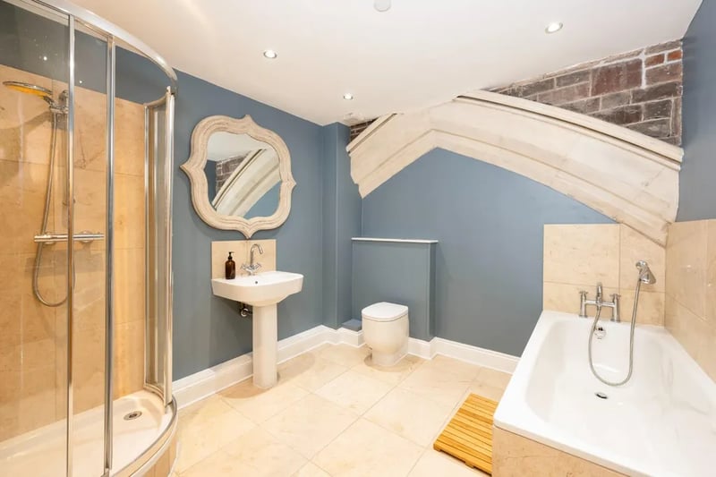 One of the property’s four bathrooms showcases the building’s original church roof timbers.