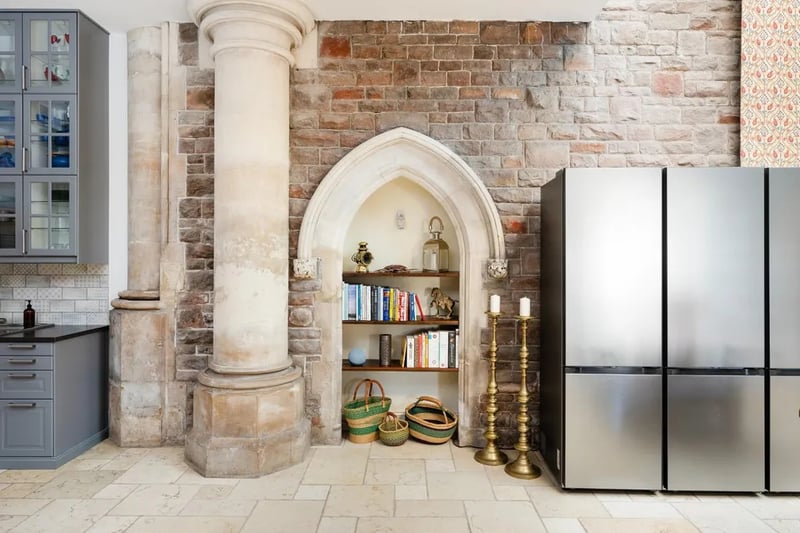 The original stone wall and carvings are displayed around the perimeter of the kitchen, with a walk-in utility room accessed from the rear corner of the room.
