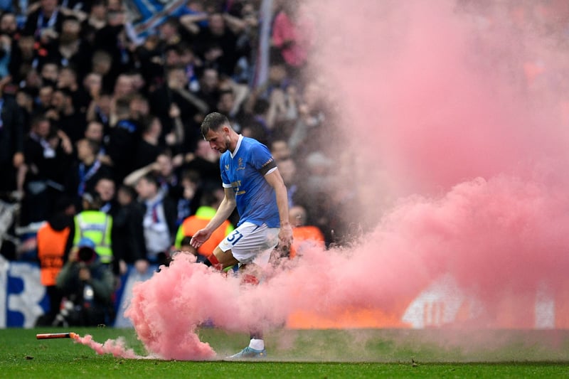 Croatian defender Borna Barisic removes a smoke bomb from the pitch after Rangers opener against the German outfit.