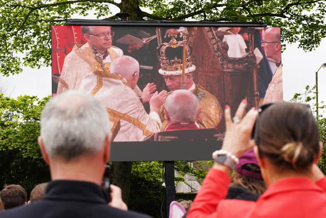 Members of the public watch the coronation of King Charles III and Queen Camilla on a big screen on the grounds of Hillsborough Castle
