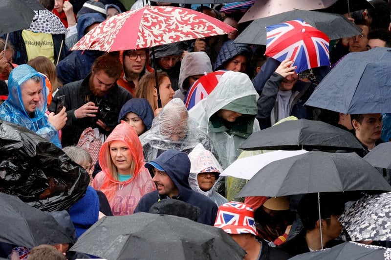 Well-wishers shelter from the rain under umbrellas. (Photo by PIROSCHKA VAN DE WOUW/POOL/AFP via Getty Images)