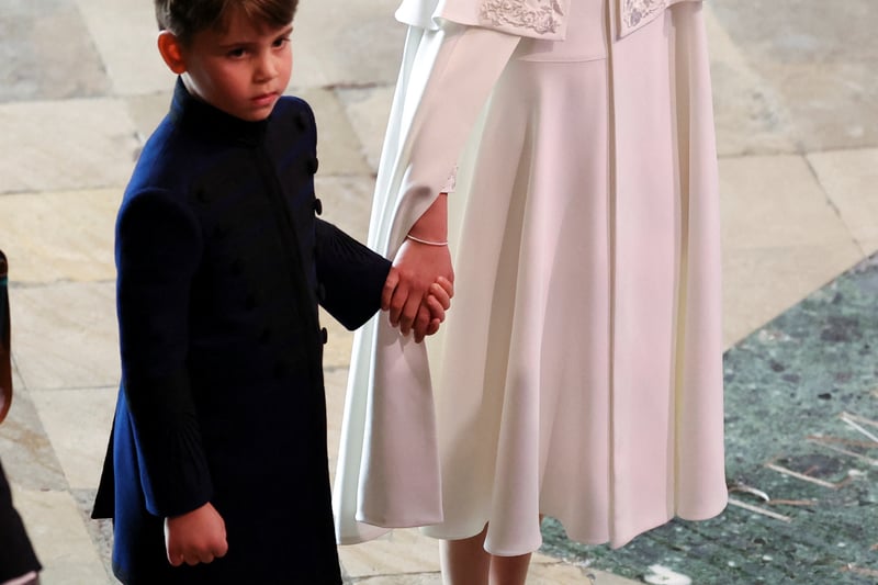 Princess Charlotte holding the hand of her younger brother, Prince Louis