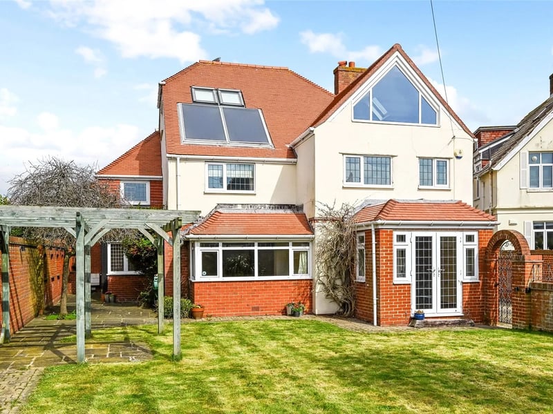 The back garden features a large lawn and a timber pergola 