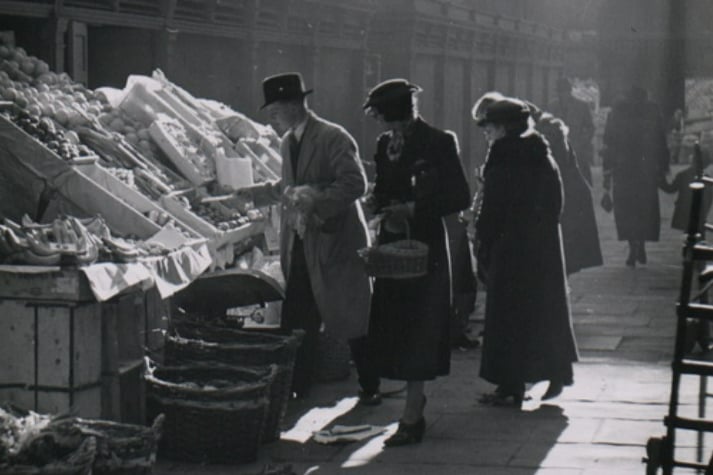 This atmospheric photo from 1938 shows well-dressed customers at the fruit and veg stall in the Glass Arcade. Photo: Bristol Archives