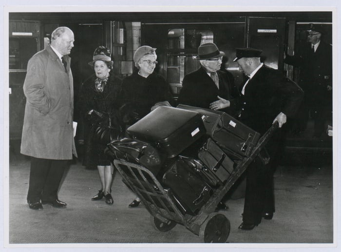 A porter helps passengers on the platform by moving their luggage on to and off the train carriages. Porters disappeared on the railways in the 1970s, with passengers having to make do with trolleys.