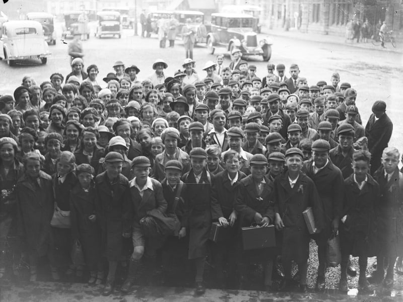 The children on this school outing can barely hide their excitement as they prepare to go inside the station with their teachers smiling in the background. Date is 1936.