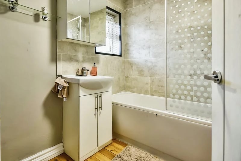 The bathroom is modern and features a bath and shower combination