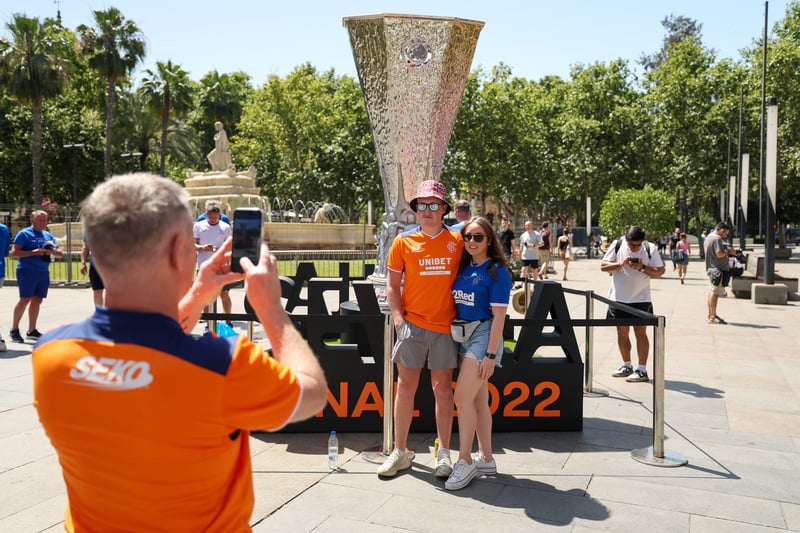 Fans pose in front of a replica UEFA Europa League Trophy in the city centre