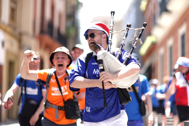 A fan playing the bagpipes is cheered on