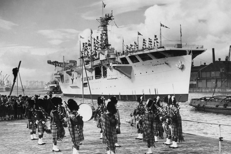 Royal Navy Nairana-class escort aircraft carrier HMS Campania is piped into port by the Glasgow Corporation Transport Pipe Band at the Festival of Britain’s exhibition ship on 19 September 1951 in Glasgow.