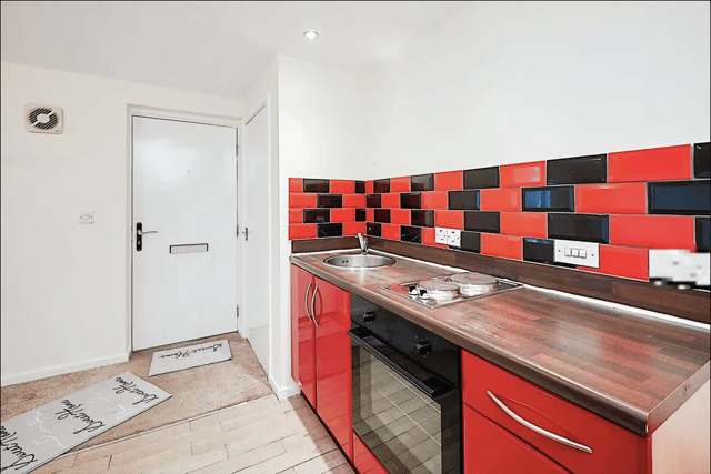 The kitchen has a red and black tile theme