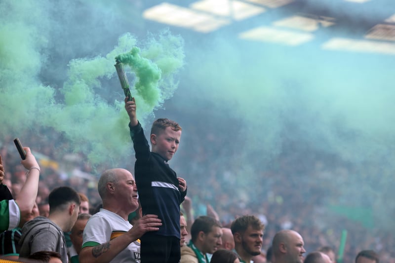 A young Celtic fan is held up as he sets off a flare during the match.