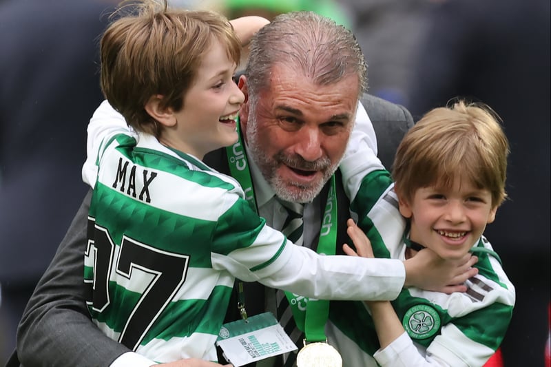 Celtic boss Ange Postecoglou receives a hug from his two sons on the pitch amid the title celebrations.