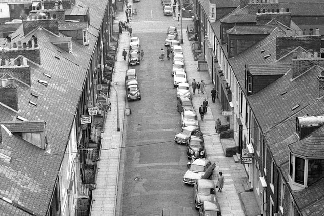 An aerial view of the street in 1962. Look at the cars and fashion of the 60s era.