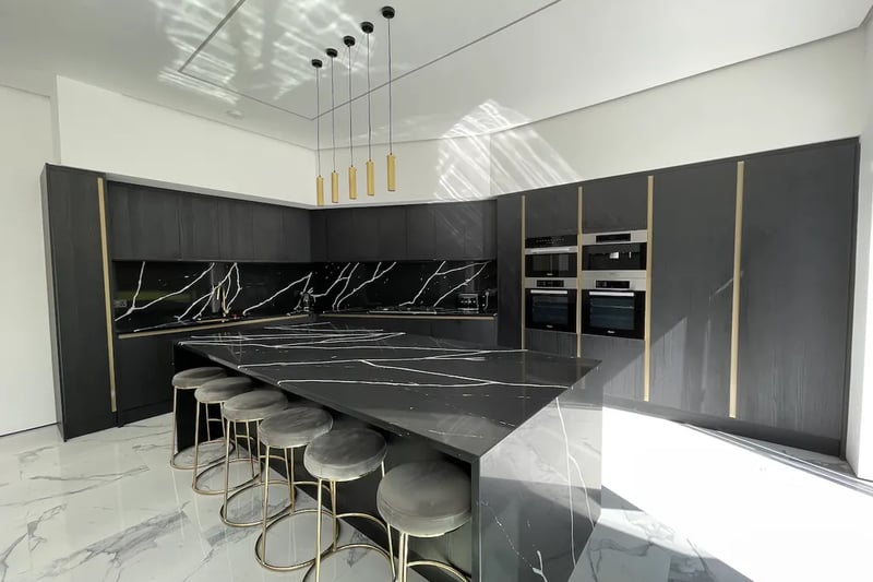 “The kitchen features a bespoke range of matte black flush base and wall units with brass trims, 1.5 sink and faucet, and a 30mm top of the range quartz countertop and backsplash, and waterfall edge 6 stool island with extra storage space.”