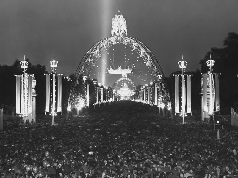A crowd of people and beneath illuminations on The Mall during the celebrations that followed the Coronation of Elizabeth II, in Westminster, London, England, 2nd June 1953