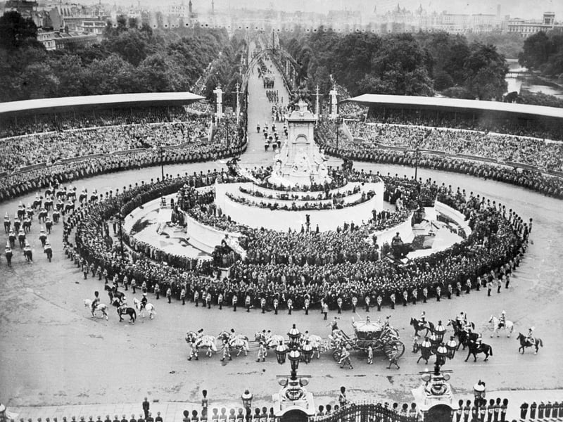 The royal carriage of Queen Elizabeth II passes by the Queen Victoria's monument, in front of Buckingham Palace, on June 02, 1953