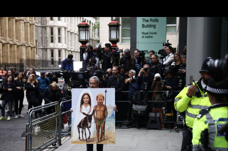 Political satire artist Kaya Mar holds a painting portraying Britain’s Prince Harry, Duke of Sussex, and his wife Meghan, Duchess of Sussex, as members of the media gather outside the Royal Courts of Justice. (Photo by HENRY NICHOLLS/AFP via Getty Images)