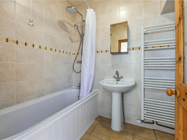 Another view of the bathroom, which has a bath with an overhead shower