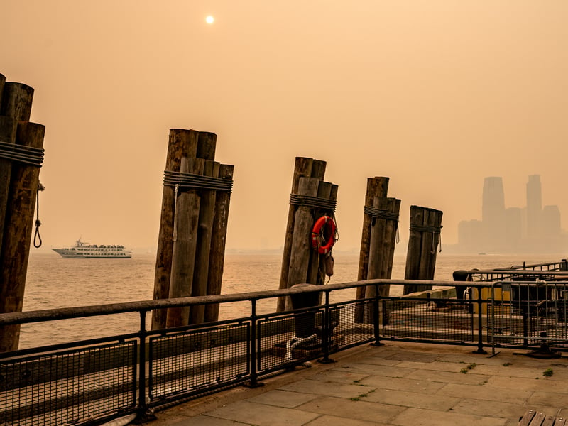 A boat can still be seen passing by Battery Park in lower Manhattan through the smoke. (Photo by David Dee Delgado/Getty Images)