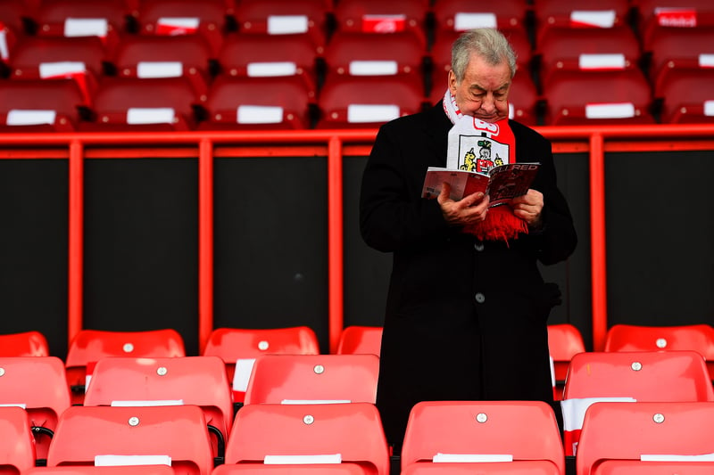 Ahead of Bristol City vs West Ham, a fan reads the match-day programme. 