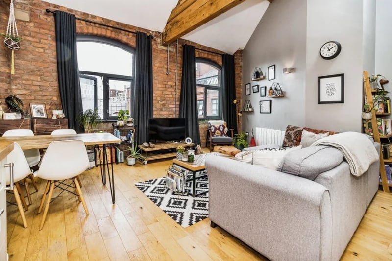 The living room also has an exposed brick wall and stunning, large windows