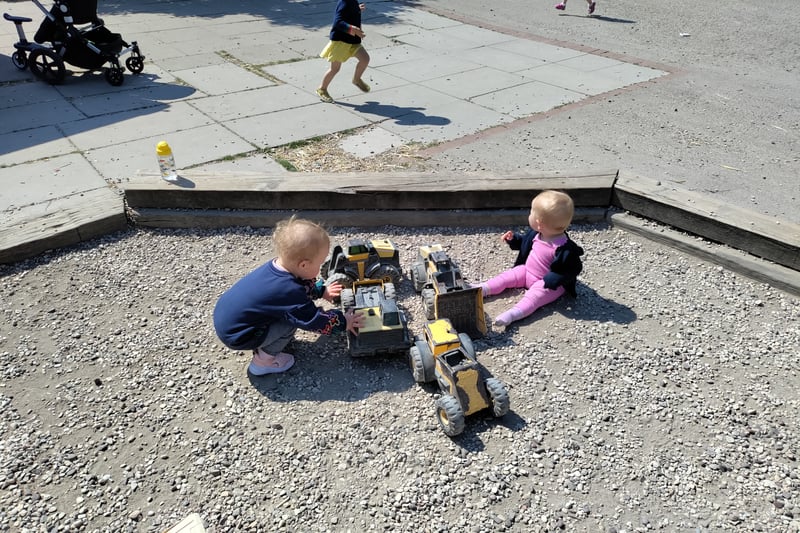Children happily play in the gravel with JCB-style toys