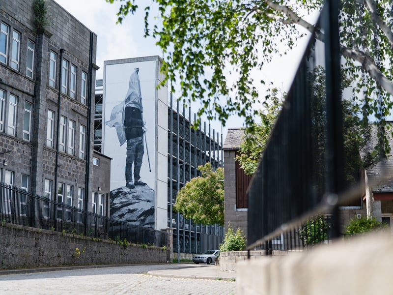 Another Spanish artist, Jofre Oliveras’ Aberdeen mural titled “The Man Who Owns The Stone” focuses on societal disconnection, meeting the theme of reconnection for Nuart 2022. Perhaps controversial for Scotland, a proud country, Oliveras thinks “nationalism obscures the vision” and that “identifying with national identity is defending the interests of the people who oppress us". Regardless, his Frederick Street mural featuring a man with his face covered by a flag is thought provoking political and continually relevant.