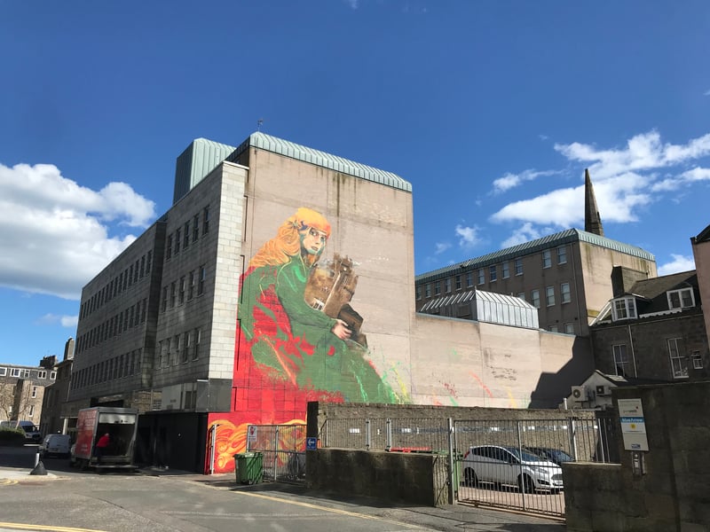 Norwegian duo Nimi and RH74 have worked together for multiple projects as part of the Stavanger festival, and in 2018 they brought their talents to Aberdeen. Their mural depicts the Green Lady of Crathes Castle, which she holds in her arms, and they were assisted by local artists Katie Guthrie and Mary Butterworth alongside graffiti artist Charlie Kelman. This is another of Nuart’s murals which call Union Plaza home.