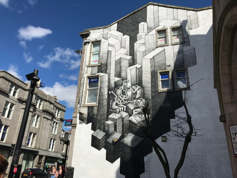Unlike some of the more colourful murals which have become part of Aberdeen’s scenery, this black and white illustration by Sheffield artist Phlegm is an apt introduction to the Granite Mile. Located on the side of the Tesco Express to the West End of the city, Phlegm’s art nods to Aberdeen’s past with a number of workers chiselling away at stone amid a quarry of giant stone pillars.