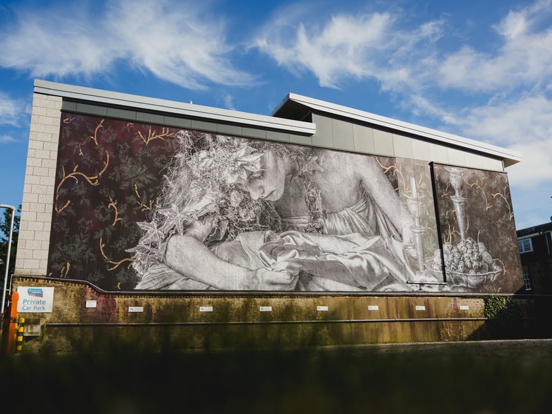 Participating in Nuart for the third time, acclaimed duo SNIK’s Thistle Lane mural is a layered and often delicate piece, which uses a combination of techniques and stencils to create a textured and often delicate artwork – despite its large scale. Florals and leaves tangle with long hair and gauzy fabrics, with hints of classical art movements, scrutinised from modern male and female perspectives. Well hidden, but certainly walkable from Union Street, this project can be found on Thistle Lane, at the back car park for the Girlguiding Aberdeen Guide Shop.