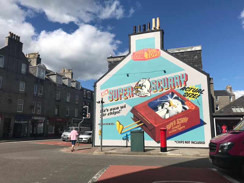 Glasgow-based duo Conzo & Glöbel, also known as Ciaran Glöbel and Conzo Throb, brought traditional sign painting techniques to the Granite City with their “Super Scurry” toy. Aberdeen’s love-hate relationship with seagulls is well documented, and locals know well enough not to eat while wandering city streets. With the wind-up toy’s affordable price of £20.18 matching the year it was installed, you can spot this mural when travelling along Holburn Street to Union Street where it sits on the corner of Willowbank Road.