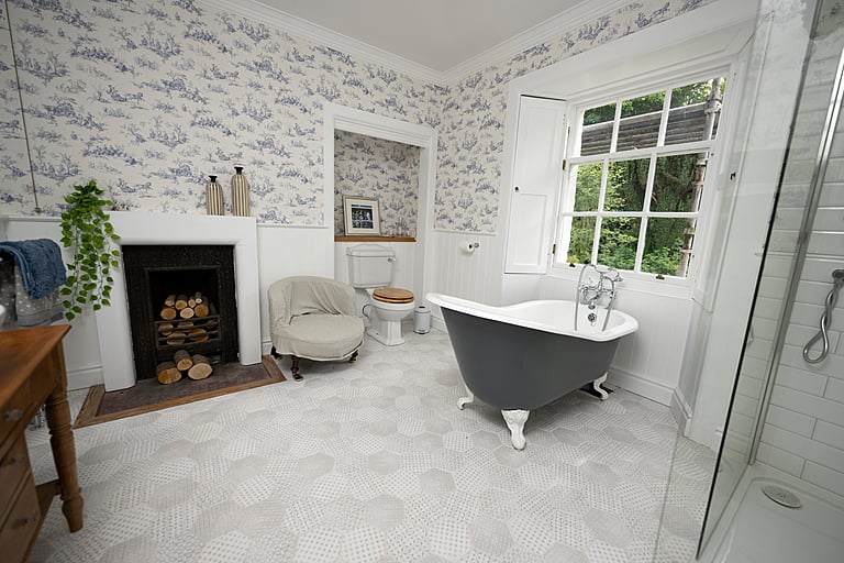 The bathroom features an original fireplace and a luxurious roll top bath