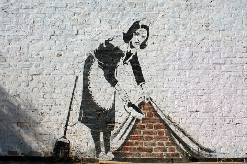 Banksy produced this piece at Chalk Farm in London. Reportedly, it is an homage to a cleaning lady named Leanne who took care of his room when he was in Los Angeles. Rather than draw the rich people that such workers serve, it serves to pay tribute to this woman and others like her who are likely to go unrecognised for their service.