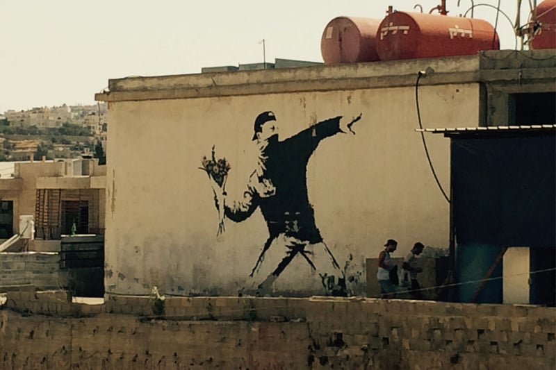 Widely considered to be the street artist’s most famous work, the “flower thrower” was painted in Jerusalem on the wall that separates Palestine from Israel. It depicts a man tossing flowers over the wall in a pose reminiscent of throwing a molotov cocktail. It is said to represent the artist’s wish for peace between their peoples.