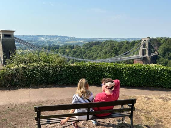 A couple take a break and enjoy the view over the Clifton Suspension Bridge from a seat outside Clifton Observatory.